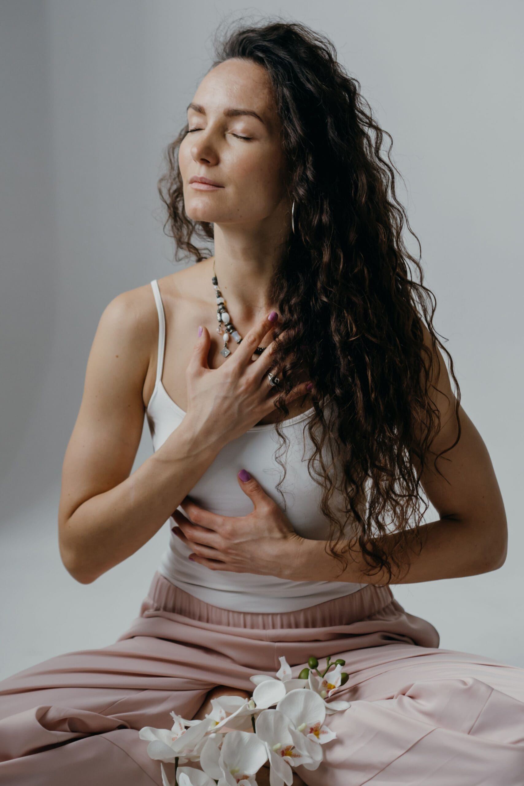 Woman with eyes closed and hand on heart representing intuition, inner connection, and spiritual awareness.