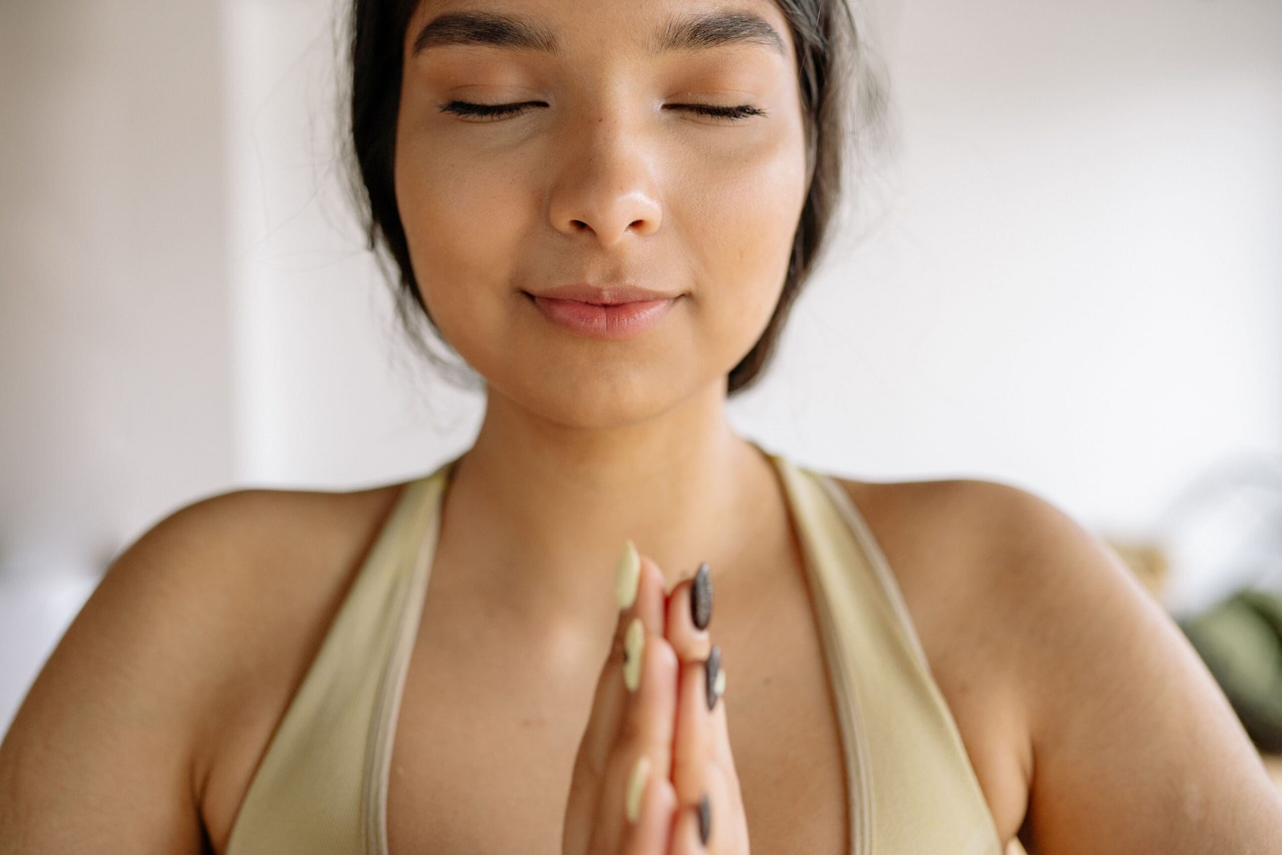 Person with hands in prayer representing meditation, sacred sound, and spiritual practice.