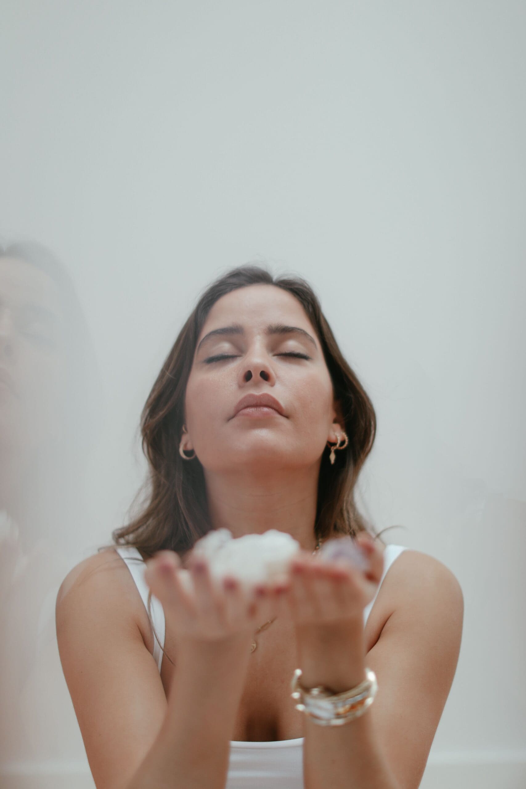 Woman with eyes closed holding crystals in open hands, representing receptivity, trust, and spiritual connection.