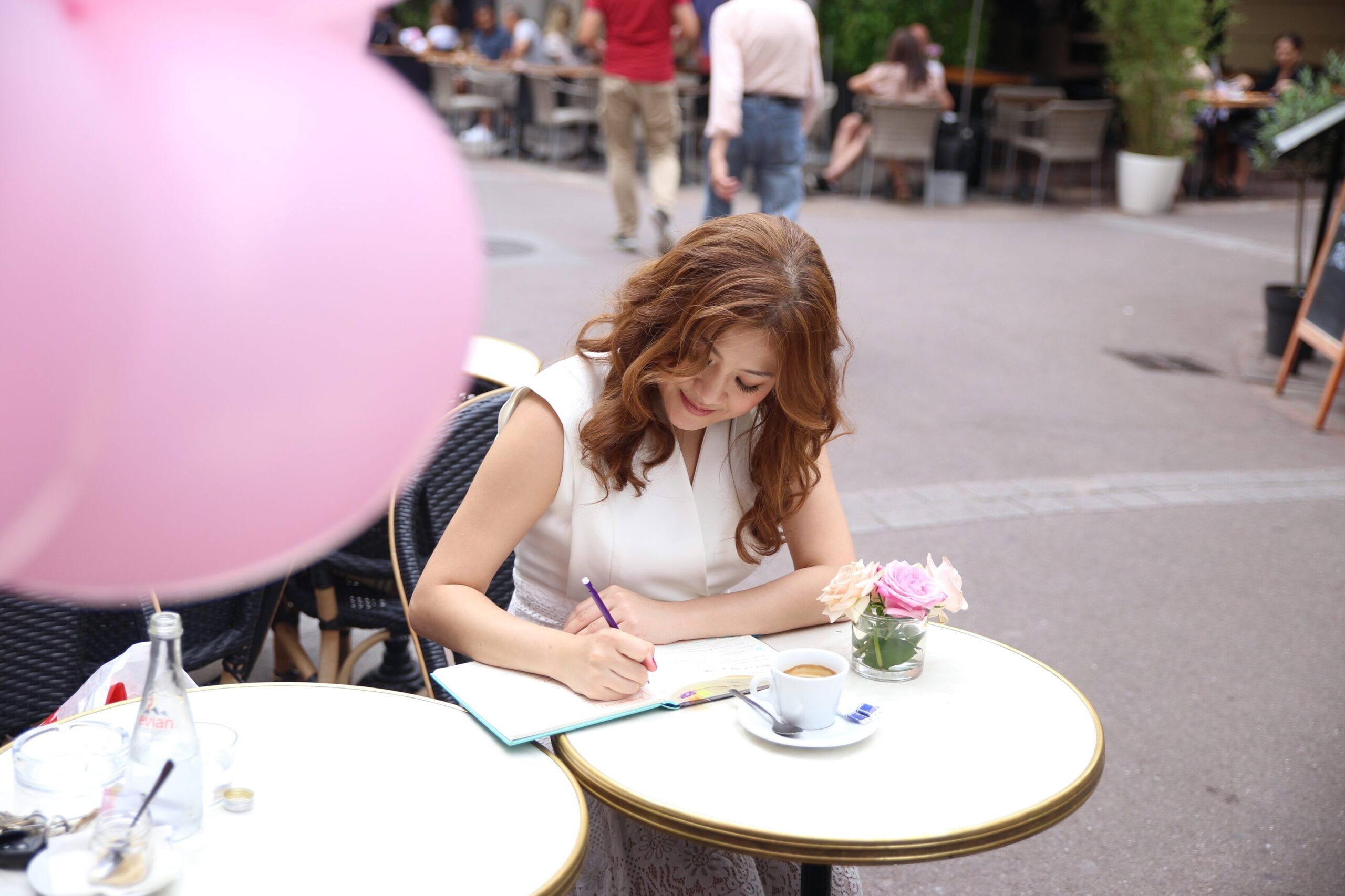 Spiritual teacher journaling at an outdoor café while reflecting on intuitive insights