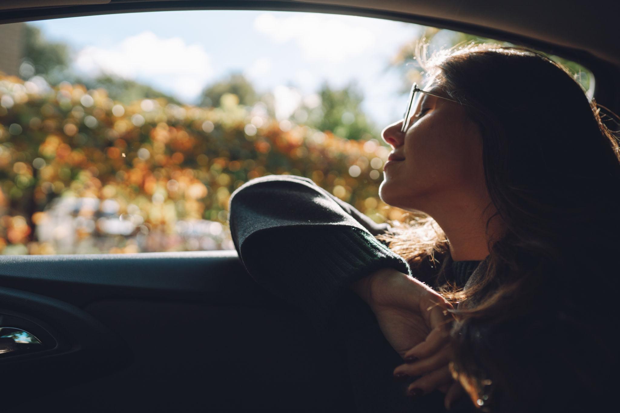 **Alt text:** Woman gazing thoughtfully out a car window during a quiet journey, illuminated by soft natural light, reflecting on an ordinary moment that became deeply meaningful.